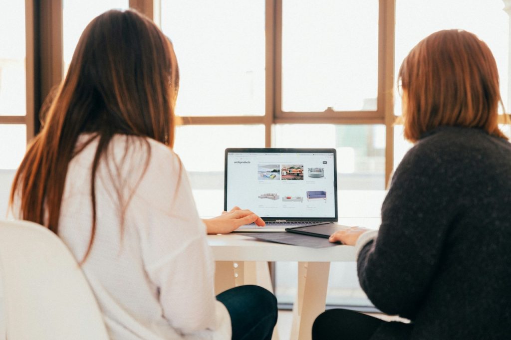 Two females working on one laptop facing away from us