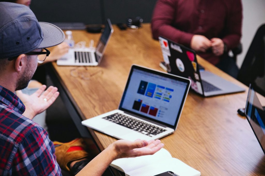 Laptops on desk and male with hands open in front of him