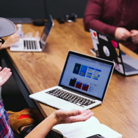 Laptops on desk and male with hands open in front of him