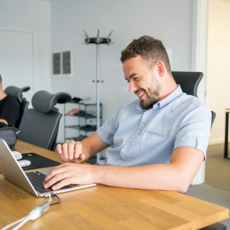Two males working at desk smiling at laptop