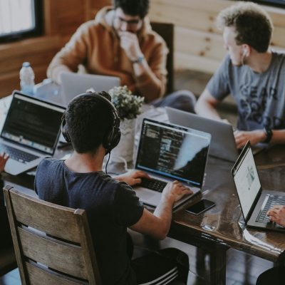 Team working at laptops around a large square desk